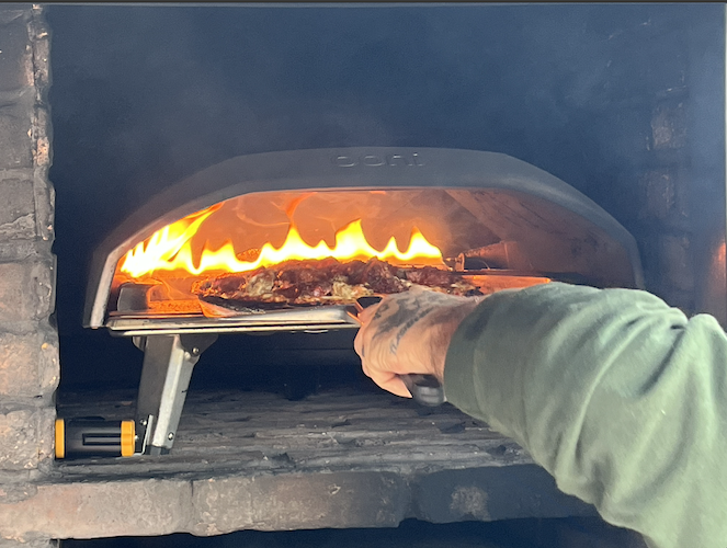 Jeremey pulls a pizza from the oven.