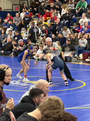 Sartor gets ready to wrestle during a match. The referee has his hand down to signal that when he puts his hand up that the match will begin.