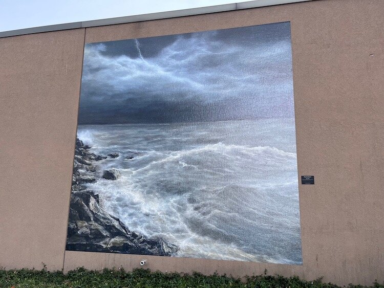 The first vinyl mural was affixed in early November to the western wall of West Marine on Water Street. The piece, “Disrupted Darkness” by Linda Kelley, "captures a moment when lighting illuminates the Lake Erie rocky shore to reveal the power and be