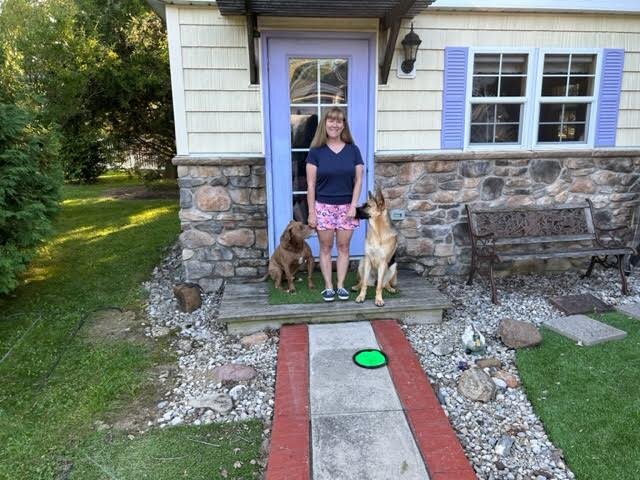 Nath stands outside of her writing cottage with her dogs, BoBo and Greta.  